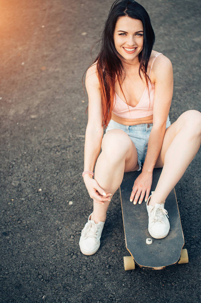 Woman with longboard sitting on the ground - Photo, image
