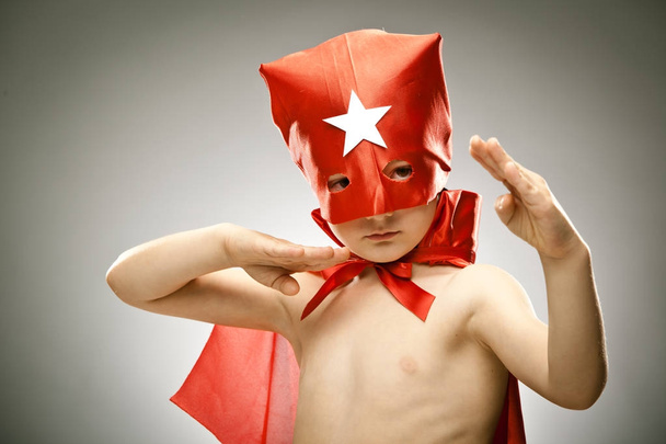 young boy superhero fly with cloak and mask portrait on grey background - Foto, Bild