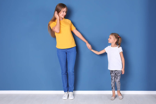 Happy mother and her daughter against color wall in children room - Fotoğraf, Görsel