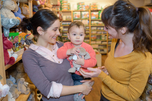 mother and daughter with attractive vendor in toy store - Photo, Image