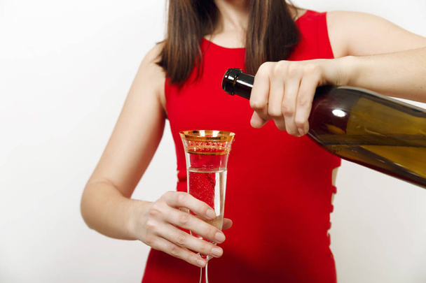 白い背景の上のグラスにボトルから注ぐシャンパンを赤いドレスの魅力的な笑顔と美しい白人幸せな女。サンタガールをすぐに分離します。新年 2018年、クリスマス ホリデー - 写真・画像