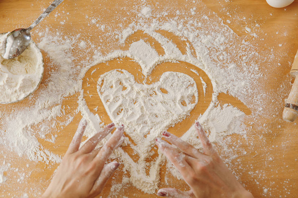 Hand drawn heart in flour on the kitchen table and other ingredients. Top view. - Photo, image