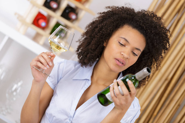 woman reading the bottle of wine label - Photo, Image