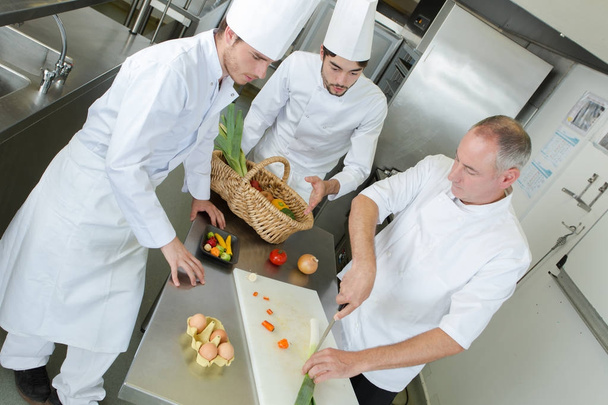 apprentices and experienced chef cooking together - Фото, зображення