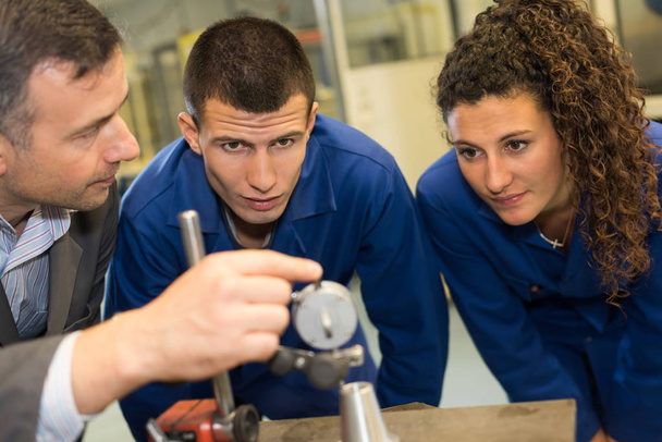 male engineer itaking precision measurement with apprentices - Photo, Image