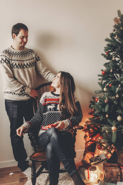 hipster family couple in sweaters sitting under Christmas tree  - Photo, Image