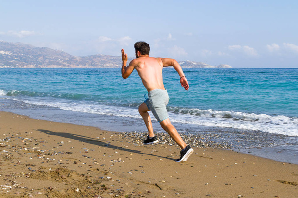 Man runner sprinting on wet sand run at the beach - Fotoğraf, Görsel