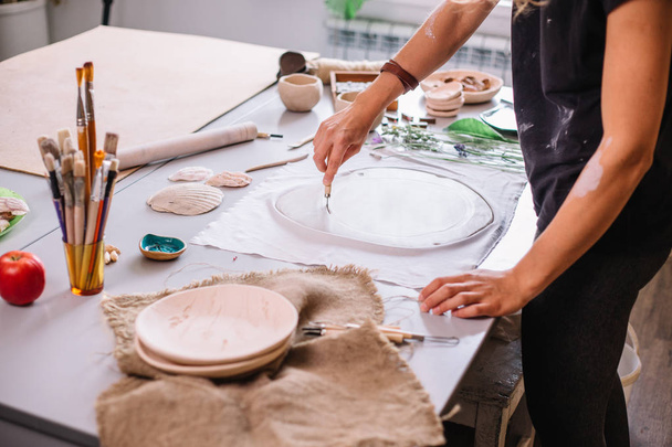 Master ceramist rubs a plate of baked clay. A creative workshop. - Photo, image