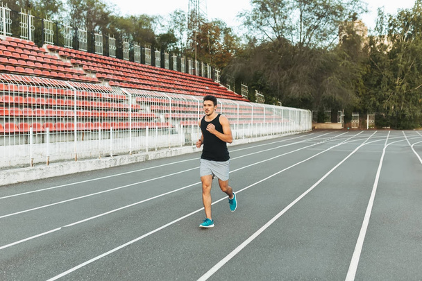 Mladý atletický muž běží na stadion v dopoledních hodinách - Fotografie, Obrázek