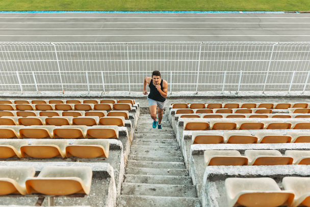 Image of young athletic man running by ladder at the stadium out - Photo, Image