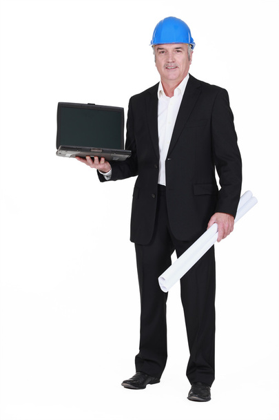 Senior businessman wearing a helmet and holding a blueprint and a laptop - Fotografie, Obrázek