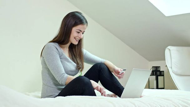 Woman Using a Laptop Sitting on a Bed at Home - 写真・画像