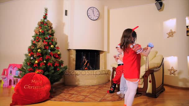 Jó újév szellemében: Mikulás, karácsonyfa, ajándék táska, kandalló - ünnepélyesen öltözött két generációs család ünnepli a téli ünnepek, a tánc és a szórakozás kamera előtt. - Felvétel, videó