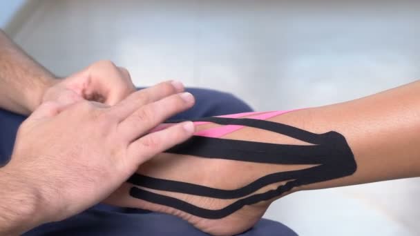 fisioterapeuta aplicando kiniesology no tornozelo do paciente feminino
 - Filmagem, Vídeo
