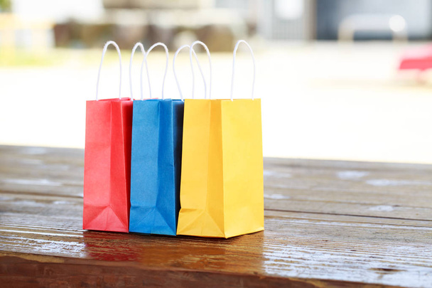 Colorful paper bags on light blurred background - Foto, imagen