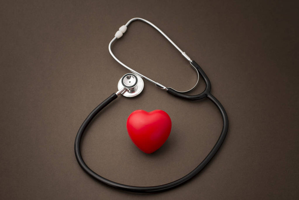 茶色の背景に聴診器で心臓を赤ゴム - 写真・画像