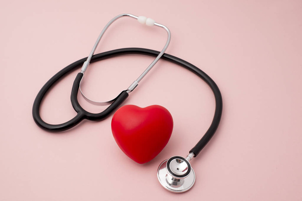 Kırmızı kalp ve pembe bir arka plan üzerinde bir stetoskop - Fotoğraf, Görsel