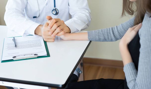 Friendly male doctor hands holding female patient hand sitting a - Photo, Image
