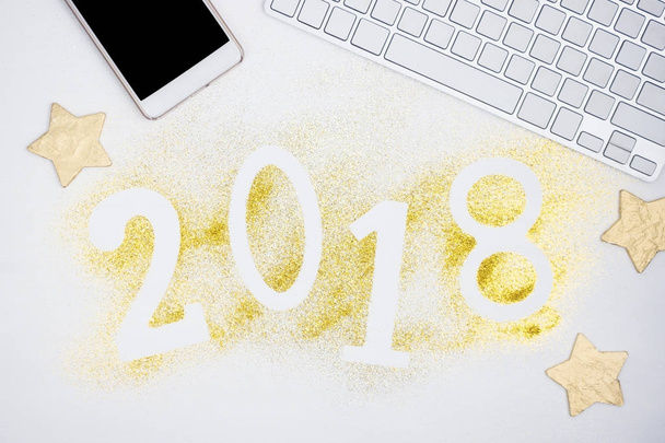 Numéros lumineux de luxe 2018 fabriqués à partir de paillettes dorées brillantes sur table blanche avec clavier et téléphone portable. Nouvelle année concept. Espace texte
 - Photo, image