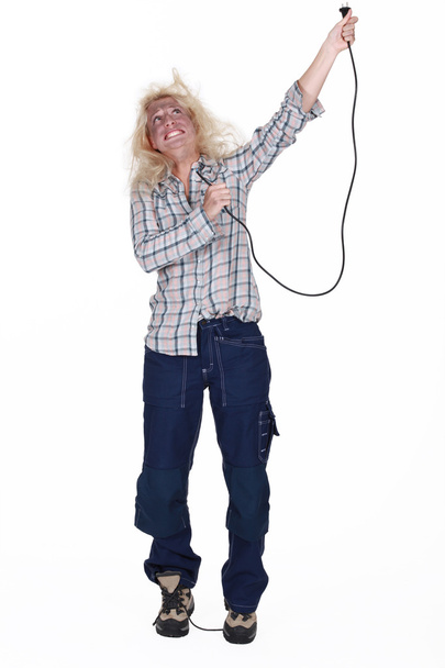 Shocked female electrician holding cable - Zdjęcie, obraz