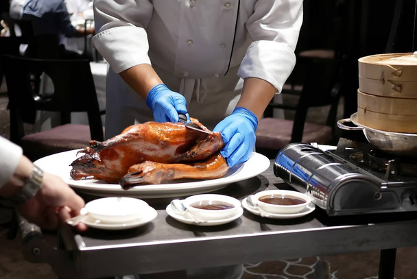 Movimiento del chef cortando pato asado en un plato para el cliente dentro del restaurante chino
 - Foto, imagen