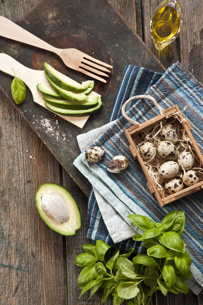top view of Quail eggs, avocado and other ingredients for spring salad. Dietary healthy food on rustic wooden background.  - Foto, afbeelding