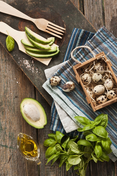 top view of Quail eggs, avocado and other ingredients for spring salad. Dietary healthy food on rustic wooden background.  - Foto, imagen
