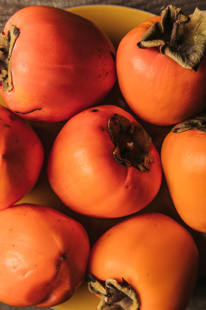 top view of ripe orange persimmons on plate - Valokuva, kuva