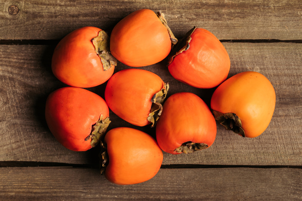 top view of ripe persimmons on wooden table - Φωτογραφία, εικόνα