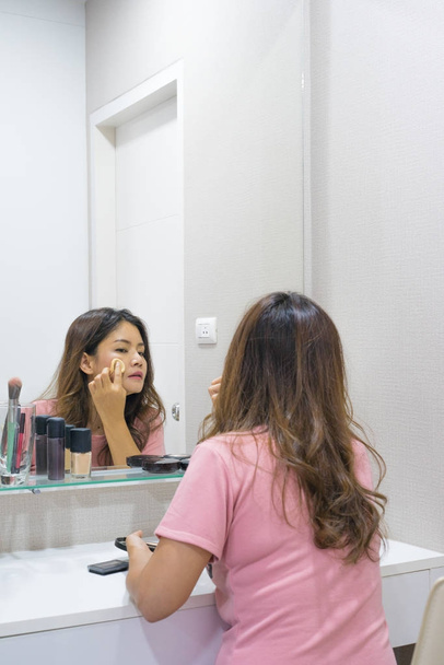 Ázsiai nő púderpamacs alkalmazása az arcát a tükörben - Fotó, kép