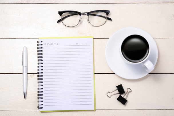 Stift, Brille, Kaffee und Notizblock auf dem Tisch - Foto, Bild
