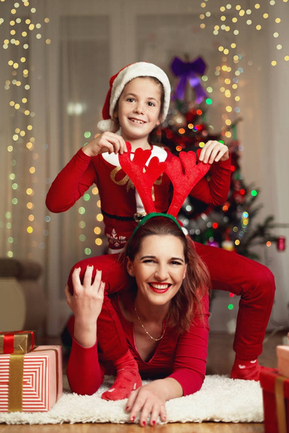 Cute girl and her mother on a Christmas Eve, having fun - Foto, Imagen