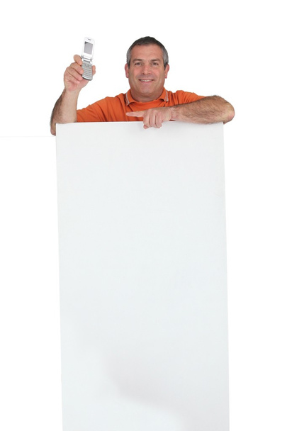 Handyman standing behind a blank sign and pointing to his mobile phone - Foto, immagini