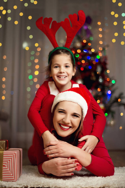 Cute girl and her mother on a Christmas Eve, having fun - Photo, Image
