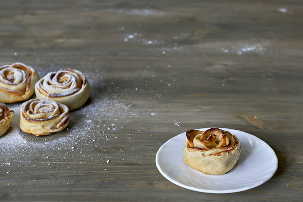 Słodkie i pyszne pieczone rose kształt ciasta z apple wypełnienia na biały talerz na podłoże drewniane proszku z cukru pudru - Zdjęcie, obraz