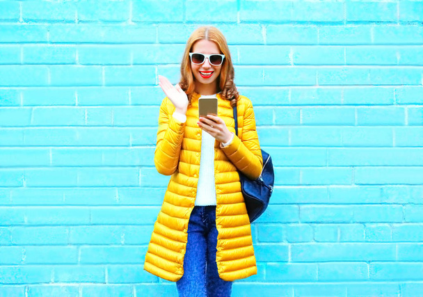 Fashion laughing woman using smartphone on a blue brick backgrou - Foto, Imagem