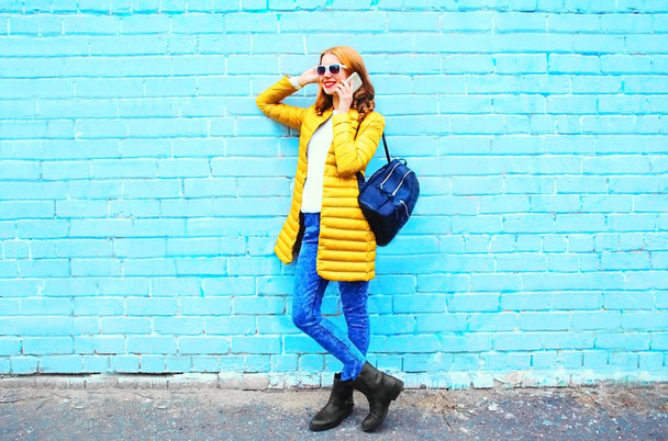 Fashion smiling woman talks on a smartphone on a blue brick back - Φωτογραφία, εικόνα