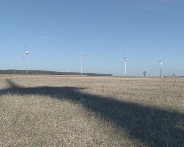 Shadow of rotating windmill on ground and windmill in distance. - Footage, Video