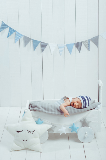 portrait of adorable infant baby in hat sleeping in wooden baby cot decorated with stars - Photo, Image