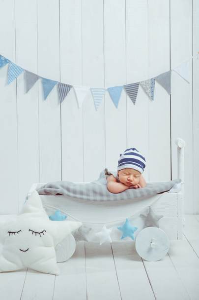 portrait of adorable infant baby in hat sleeping in wooden baby cot decorated with stars - Photo, Image