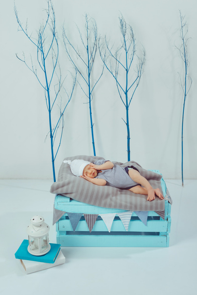 ボディー スーツと帽子で近くのランタンと木製の箱に眠る愛らしい新生児 - 写真・画像