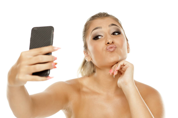junge schöne Frau macht Selfie auf weißem Hintergrund - Foto, Bild