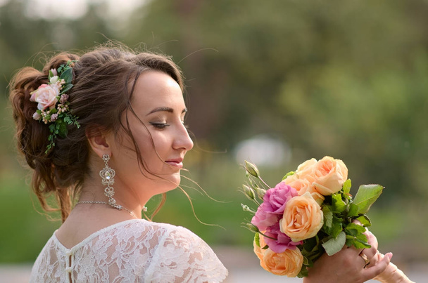 Incroyablement belle mariée avec bouquet de roses. Accessoire romantique de fiancée. Longue fille aux cheveux en robe de mariée
 - Photo, image