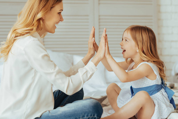 Joyful nice mother and daughter playing a clapping game - Foto, Bild