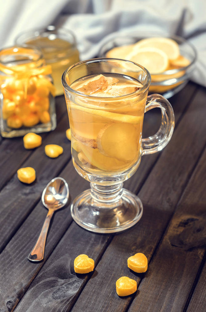 Composition from tea with lemon and ginger and yellow sweets close up - Φωτογραφία, εικόνα