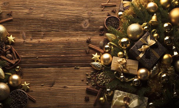 Decoración navideña en estética dorada y marrón con regalos en cajas, adornos dorados, especias navideñas todo sobre un fondo rústico de madera con espacio para copiar
. - Foto, Imagen