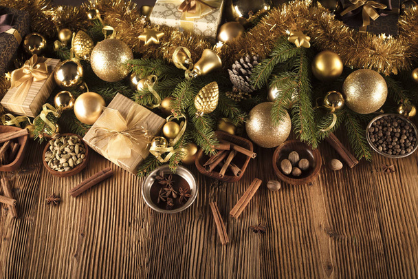 Decoración navideña en estética dorada y marrón con regalos en cajas, adornos dorados, especias navideñas todo sobre un fondo rústico de madera con espacio para copiar
. - Foto, Imagen