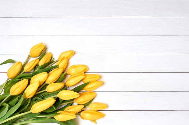 Kytice ze žlutých tulipánů na bílém pozadí dřevěná. Pohled shora, kopie prostor - Fotografie, Obrázek