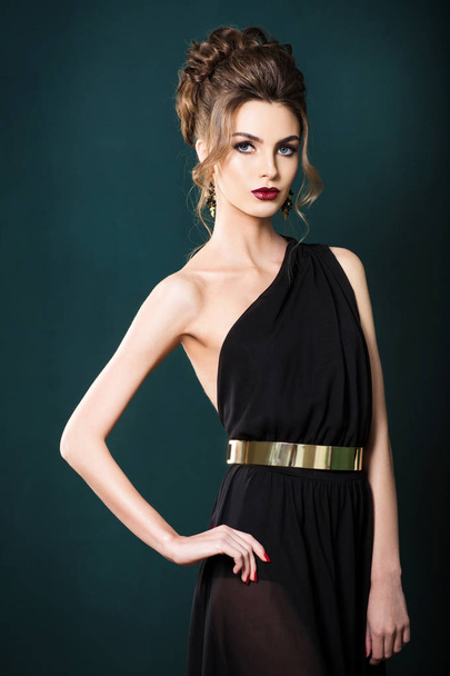 beautiful woman with hairstyle in elegant black dress on green wall background - Valokuva, kuva