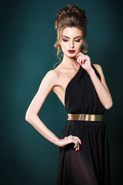 beautiful woman with hairstyle in elegant black dress on green wall background - Zdjęcie, obraz
